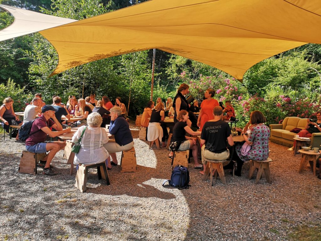 Ein Bild einer Menschengruppe, die bei gutem Wetter draußen gemeinsam essen.